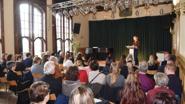 Voller Veranstaltungssaal von hinten. Am Rednerpult Frau Angela Schweers.