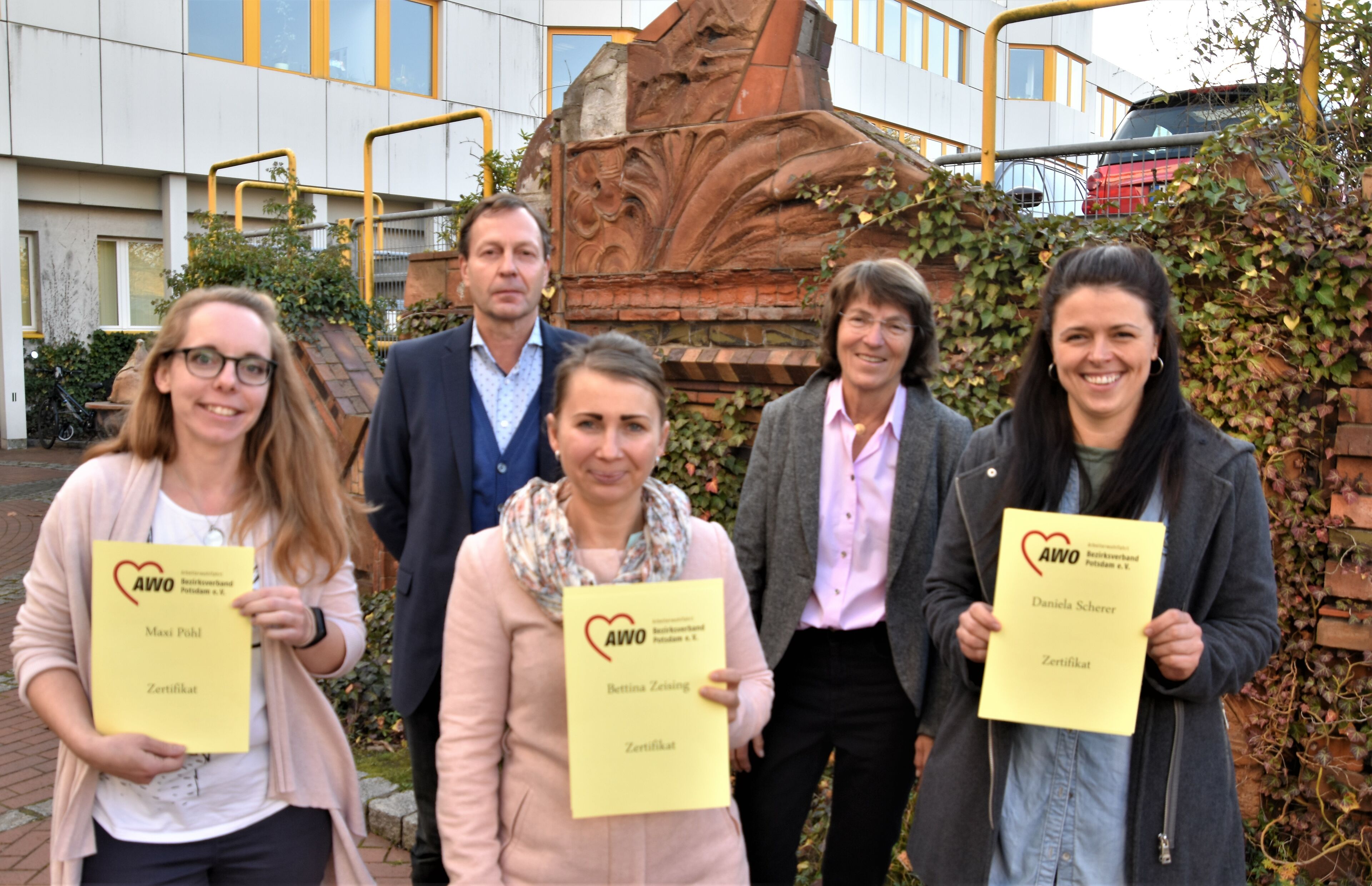 Auf dem Bild sind zu sehen im Vordergrund Bettina Zeising, Daniela Scherer und Maxi Pöhl, die ihre Zertifikate als Schulgesundheitsfachkräfte in der Hand haltern. Dahinter Stefan Zaborowski, Verantwortlich beim AWO Bezirksverband für die Zertifizierung